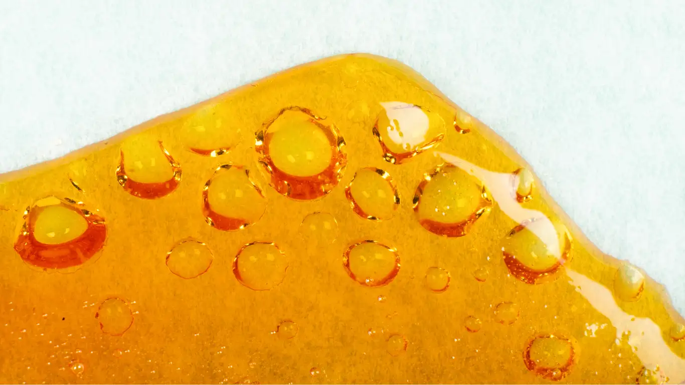 Close-up of golden cannabis concentrate with translucent bubbles.