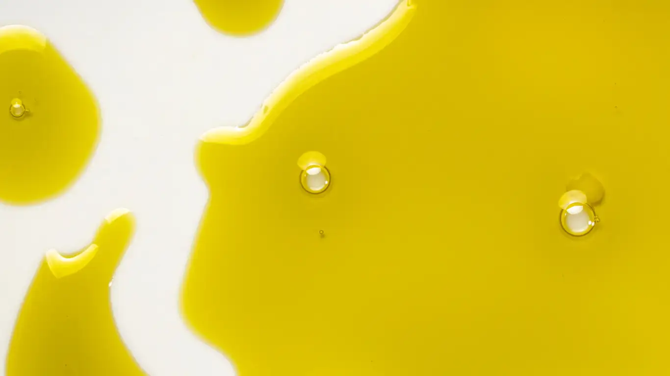 Close-up of yellow oil droplets on a white surface.